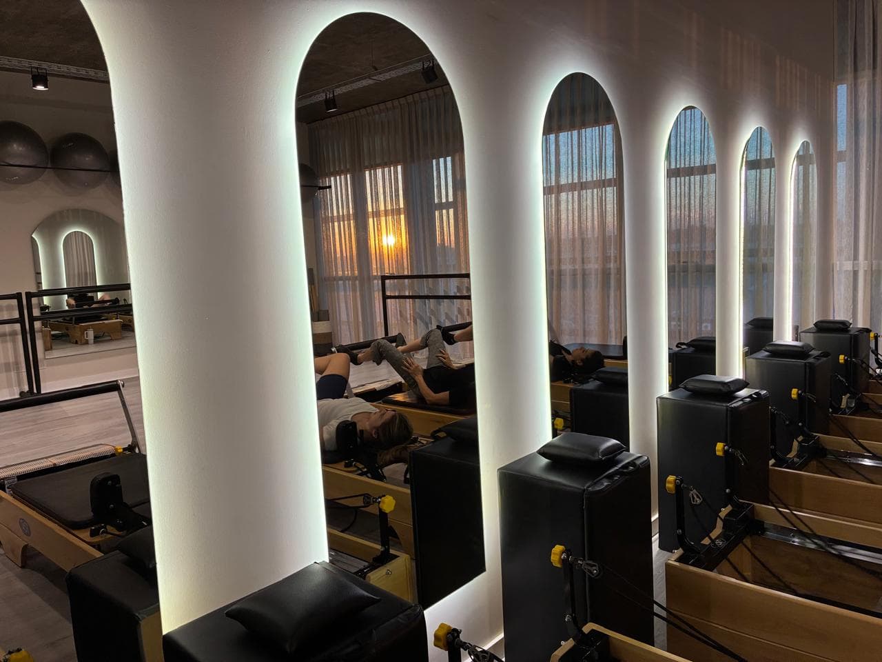 Alumnas practicando en los reformers, con los arcos iluminados al atardecer