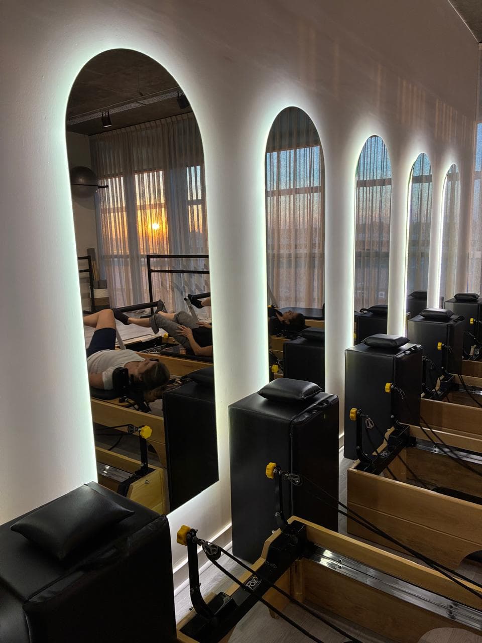 Sala de reformers de Graan Studio, con arcos iluminados y luz de atardecer